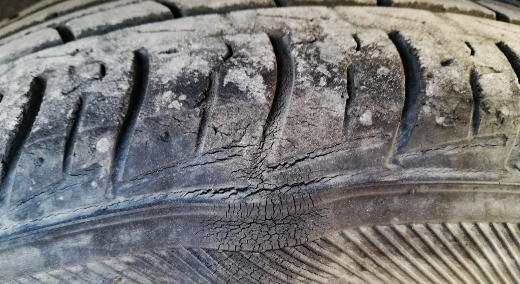 An old, cracked tire with a bubble where the sidewall meets the tread.
